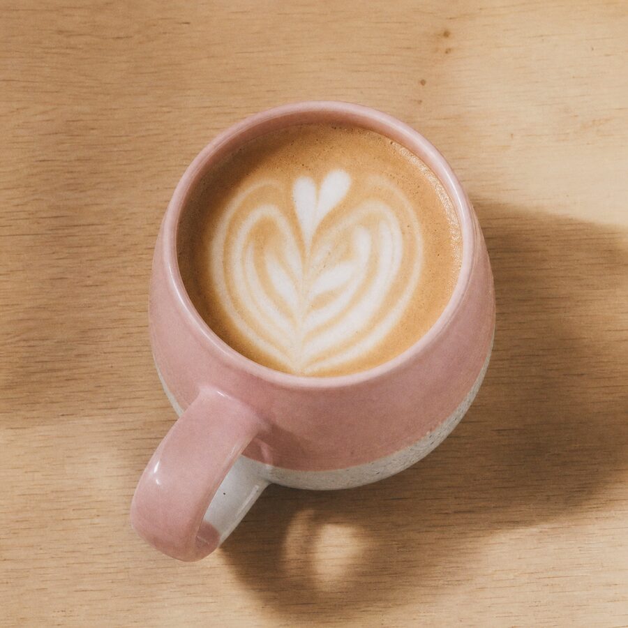 La taza vista desde arriba con café y un dibujo de espuma, mostrando el interior rosa